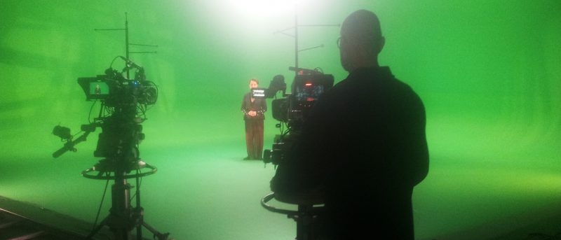 Person using camera in a green screen studio