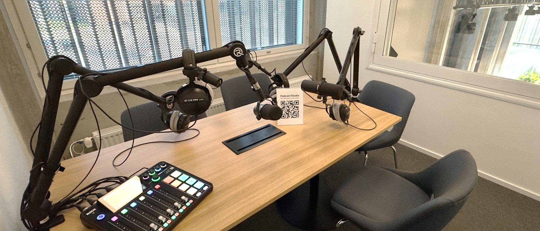 A view of the Podcast Studio, showing 4 comfy seats around a wooden table