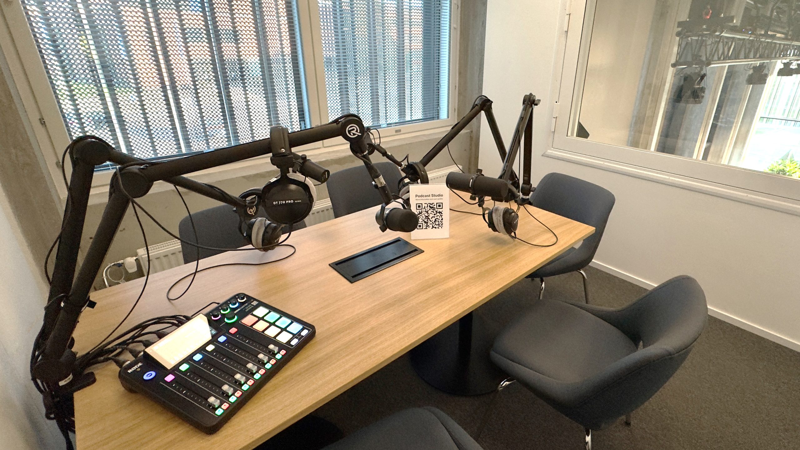 A view of the Podcast Studio, showing 4 comfy seats around a wooden table